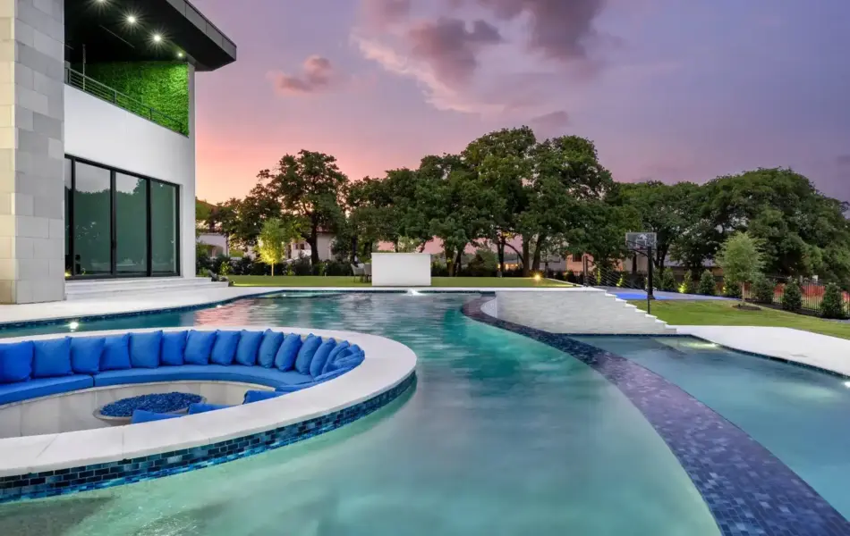 Pool side view of sunken fire pit and integrated seating in freeform pool