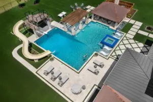 bird's eye-view of luxury pool with pool slide, integrated spa and tanning ledges