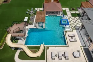 bird's eye-view of luxury pool with pool slide, integrated spa and tanning ledges
