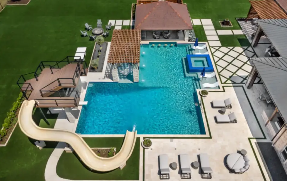bird's eye-view of luxury pool with pool slide, integrated spa and tanning ledges