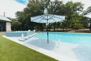 Parasol at edge of swimming pool with integrated water features